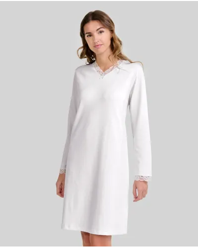 Woman wearing a classic ivory long-sleeved chemise nightdress with a V-neckline and lace trim.