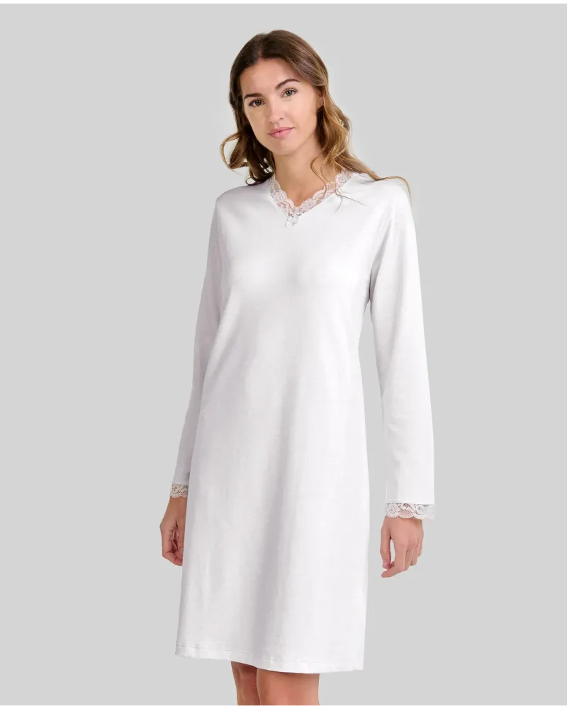 Woman wearing a classic ivory long-sleeved chemise nightdress with a V-neckline and lace trim.