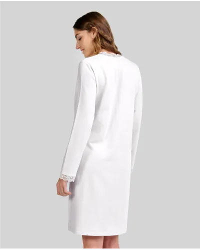 Woman wearing a classic ivory long-sleeved chemise nightdress with a V-neckline and lace trim.