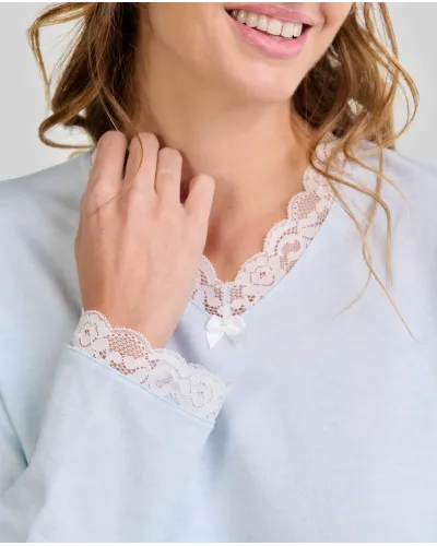 Woman wearing a classic long-sleeved sky blue chemise nightdress with a V-neckline and lace trim.