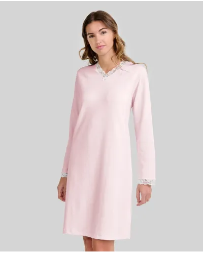 Woman wearing a pink long-sleeved chemise nightdress with a V-neckline and lace trim
