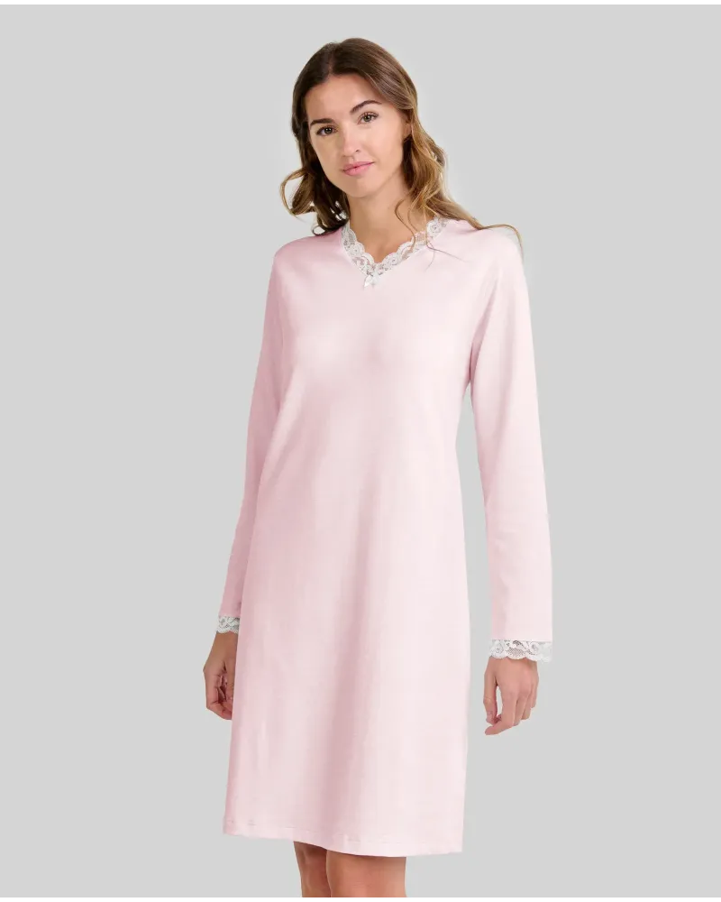 Woman wearing a pink long-sleeved chemise nightdress with a V-neckline and lace trim