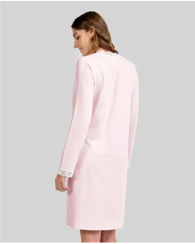 Woman wearing a pink long-sleeved chemise nightdress with a V-neckline and lace trim