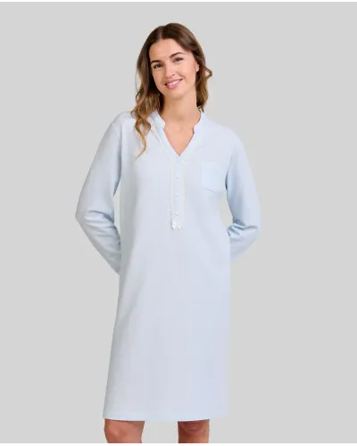 Woman wears a sky blue winter nightdress with a button-down collar and lace and bow details.