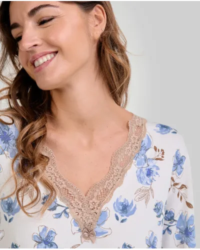 Woman wearing a long-sleeved winter nightgown with blue flowers and lace at the neckline