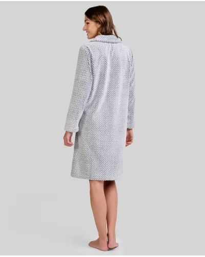 Mujer de pie descalza con bata larga gris claro y textura espiga, botones al frente y manos en los bolsillos