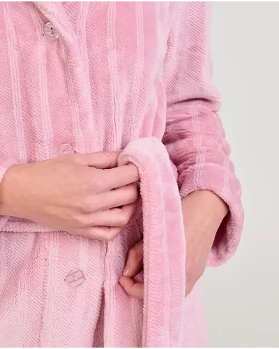 Woman wearing a pink jacquard wrap-around robe with stripes, pockets and a belt.