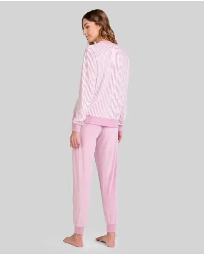 Woman wearing comfortable light pink microfleece pyjamas with a striped T-shirt and plain trousers