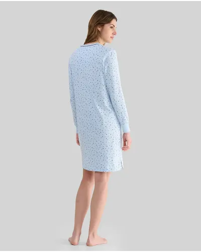 Woman wearing a light blue long-sleeved nightdress with small flowers and an open neckline with buttons and a bow