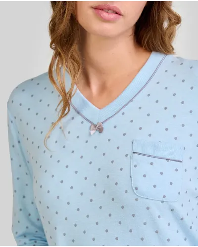 Woman wearing a light blue long-sleeved nightdress with a small polka dot pattern and pocket