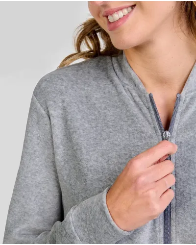 Woman posing in a grey pyjama set with a zip-up jacket with pockets and matching trousers.