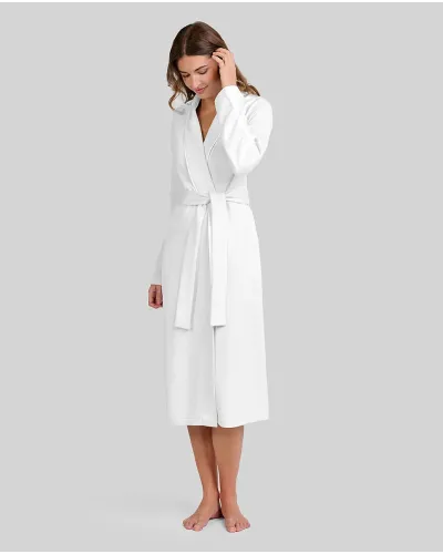 Woman wearing a long ivory lace-up dressing gown with pockets, tuxedo collar and piping