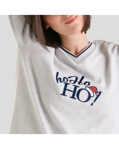 Woman in long Christmas pyjamas with plain embroidered V-neck top and matching navy checked trousers.