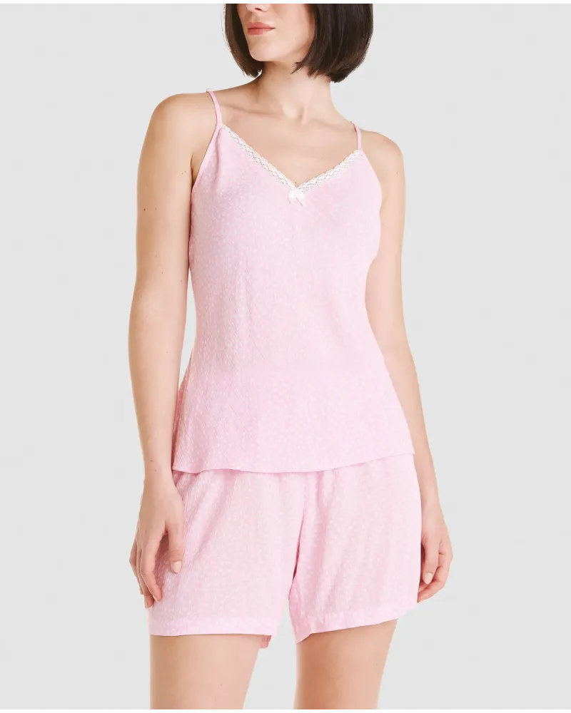 Woman wearing a pink summer pyjama set with straps, lace-up neckline and shorts. White polka dot print.