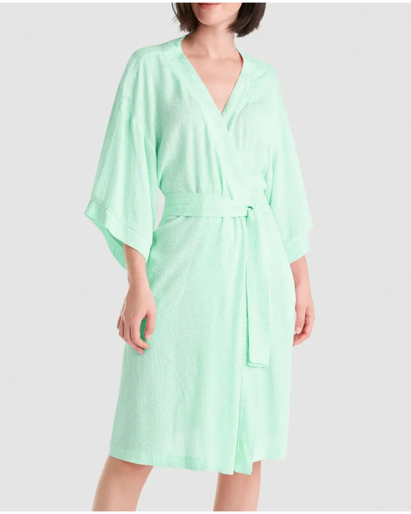 Mujer con bata corta veraniega de viscosa verde estampada a topitos, bolsillos laterales, cinturón y manga francesa