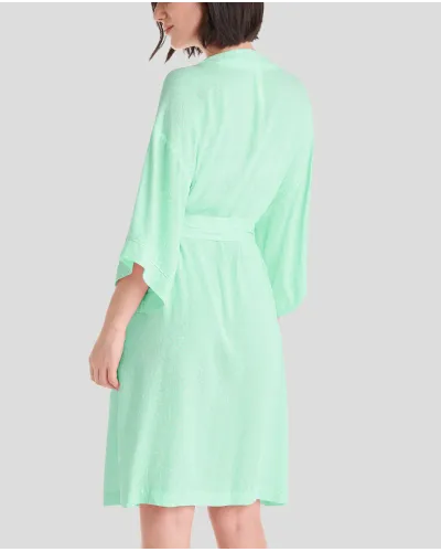 Woman in green viscose summer short dressing gown with polka dot print, side pockets, belt and French sleeves.