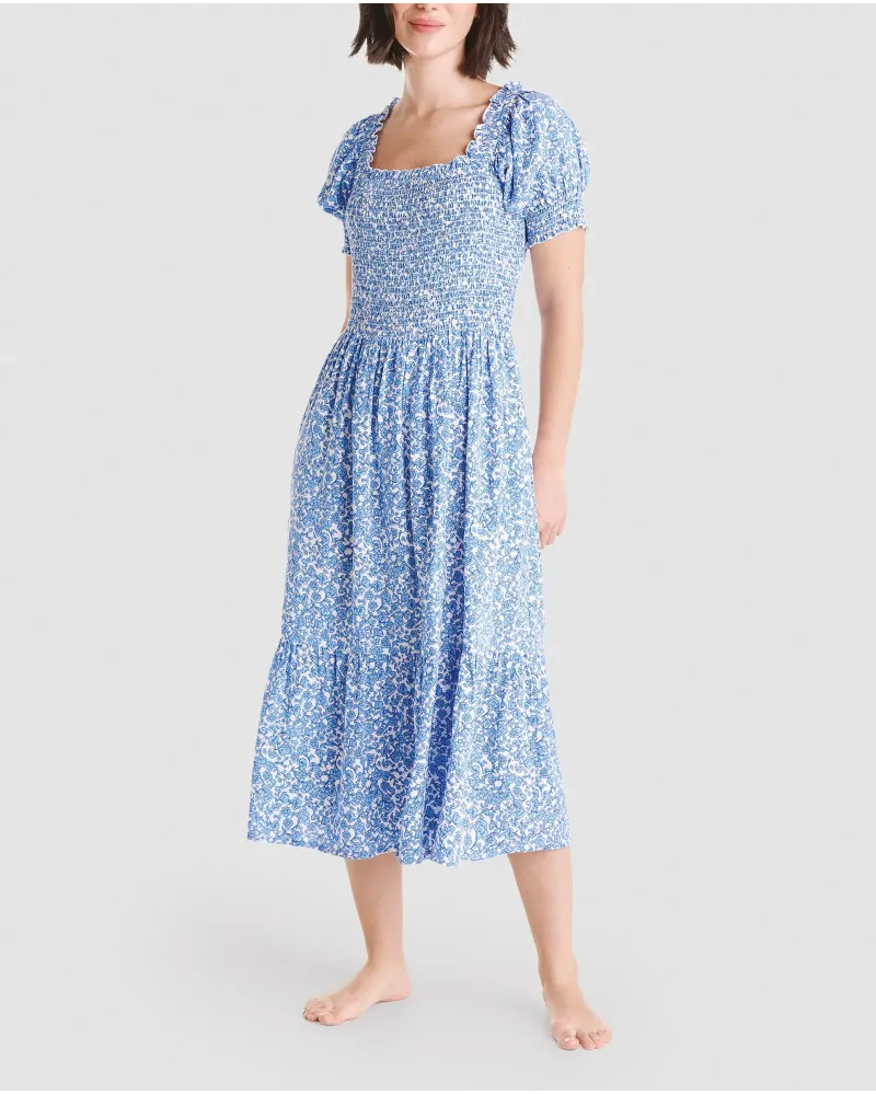 Woman in long blue flowered dress with short sleeves, honeycomb top and square neckline