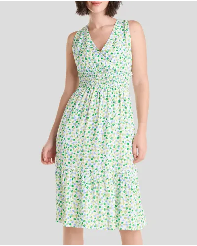 Model wears short sleeveless summer dress in pistachio green with polka dots and honeycomb waistband