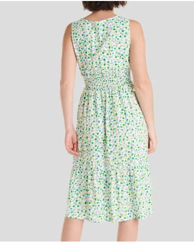 Model wears short sleeveless summer dress in pistachio green with polka dots and honeycomb waistband