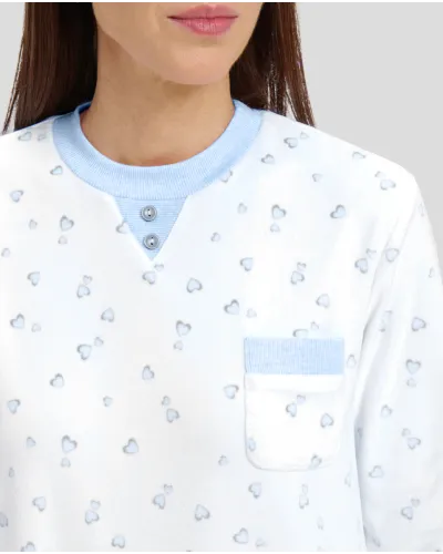 Woman in ivory winter pyjamas with light blue hearts and detailing on collar, pocket and cuffs