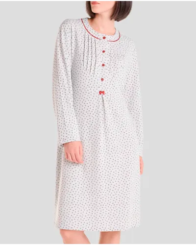 Woman wearing a long winter nightdress with a floral print, pleats and red detailing.