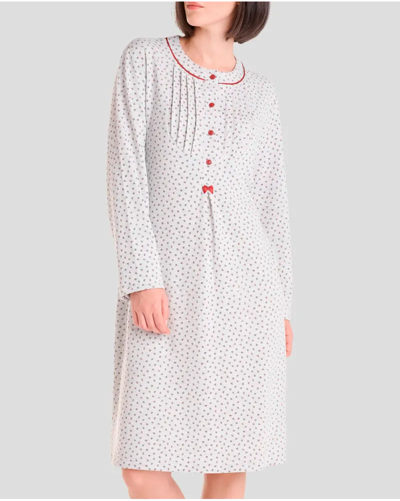 Woman wearing a long winter nightdress with a floral print, pleats and red detailing.
