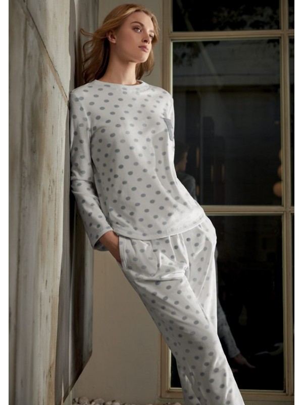 Model poses by window in long-sleeved pyjamas with silver polka dot round neck.