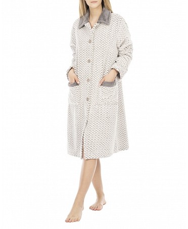 A woman dressed in an elegant long buttoned white and grey jacquard zig zag buttoned dressing gown.
