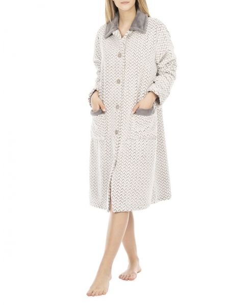 A woman dressed in an elegant long buttoned white and grey jacquard zig zag buttoned dressing gown.