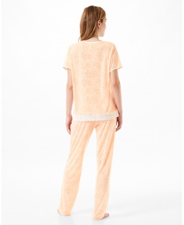 Vista trasera de una mujer vistiendo un conjunto de pijama color melocotón.