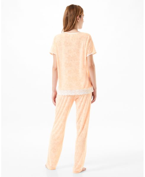 Vista trasera de una mujer vistiendo un conjunto de pijama color melocotón.