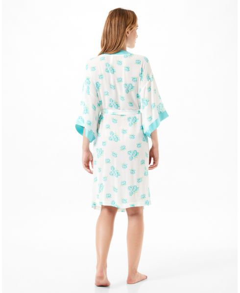 Woman with her back turned in a short floral summer gown with turquoise satin French sleeves.