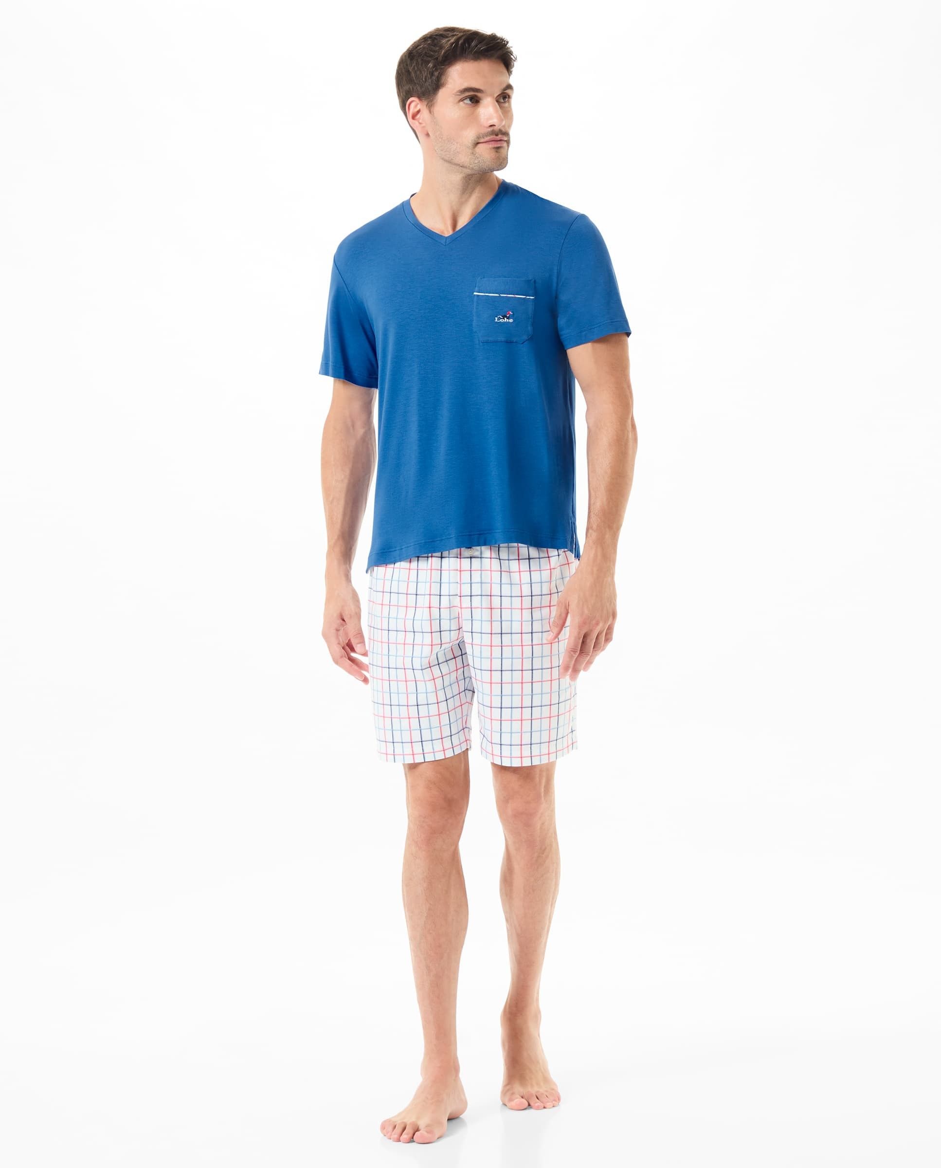 Man wears short summer pyjamas with blue T-shirt and check print trousers.