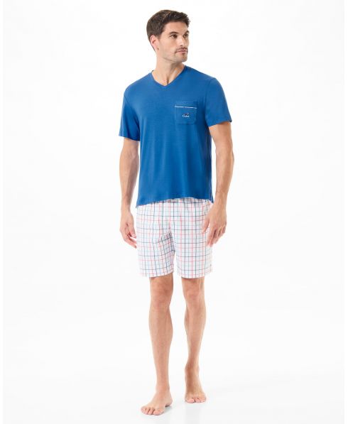 Man wears short summer pyjamas with blue T-shirt and check print trousers.