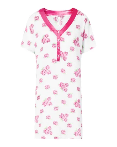 Una mujer luciendo un camisón corto blanco con flores color fucsia y cuello de raso a juego.