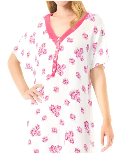 Una mujer luciendo un camisón corto blanco con flores color fucsia y cuello de raso a juego.