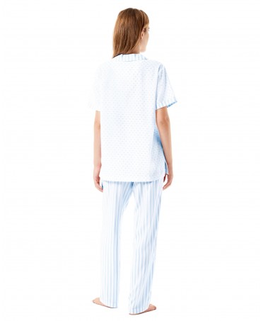 Back view of a woman wearing long summer pyjamas in blue and white plumeti.