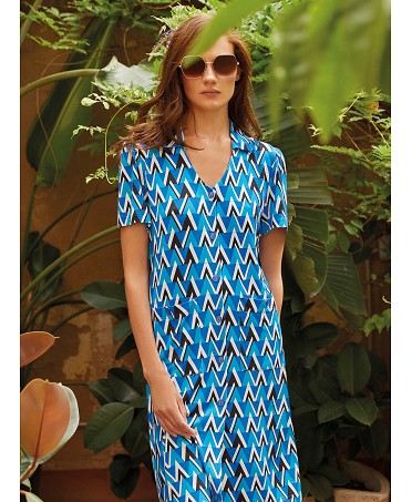 Mujer posa en jardín con vestido corto de verano abierto con botones con cuello pico