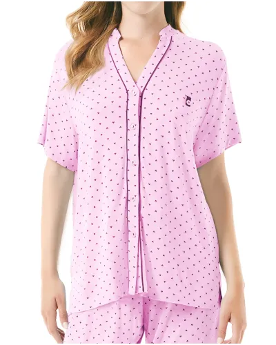 A woman wears a pink short-sleeved pyjama set with little hearts.