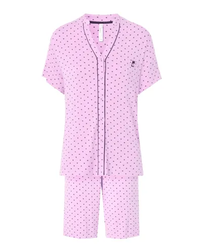 A woman wears a pink short-sleeved pyjama set with little hearts.