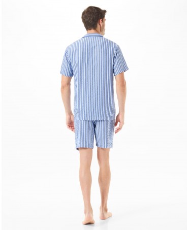 Man with his back turned in short-sleeved summer pyjamas and blue striped shorts.