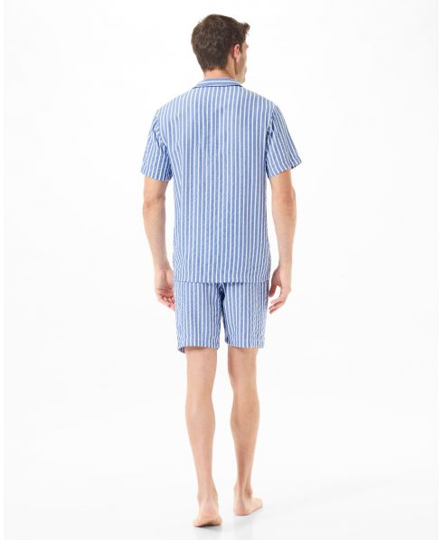 Man with his back turned in short-sleeved summer pyjamas and blue striped shorts.
