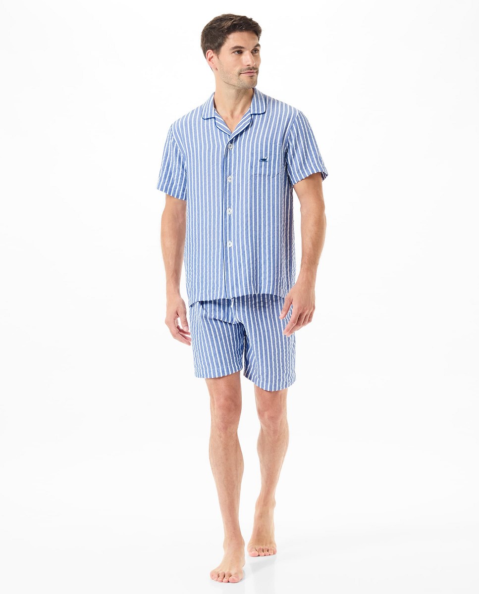 A man wearing a blue and white striped open short pyjama set.