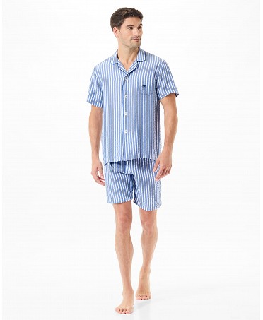 Un hombre luciendo un conjunto de pijama corto abierto a rayas en azul y blanco.