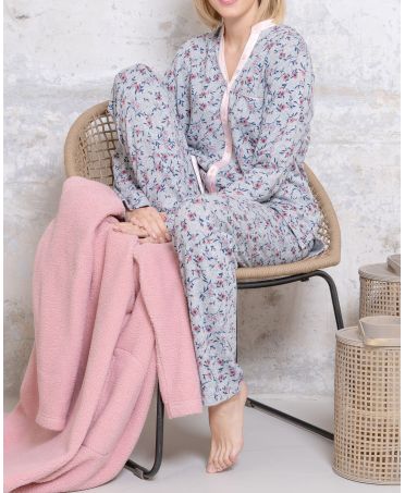 Woman with long winter pyjamas open with buttons and flower print in shades of grey and pink.