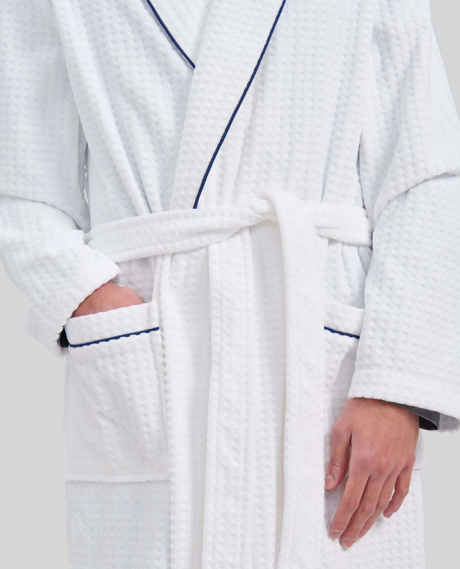 Vista detalle de albornoz blanco de hombre con bolsillos y detalles de vivo azul