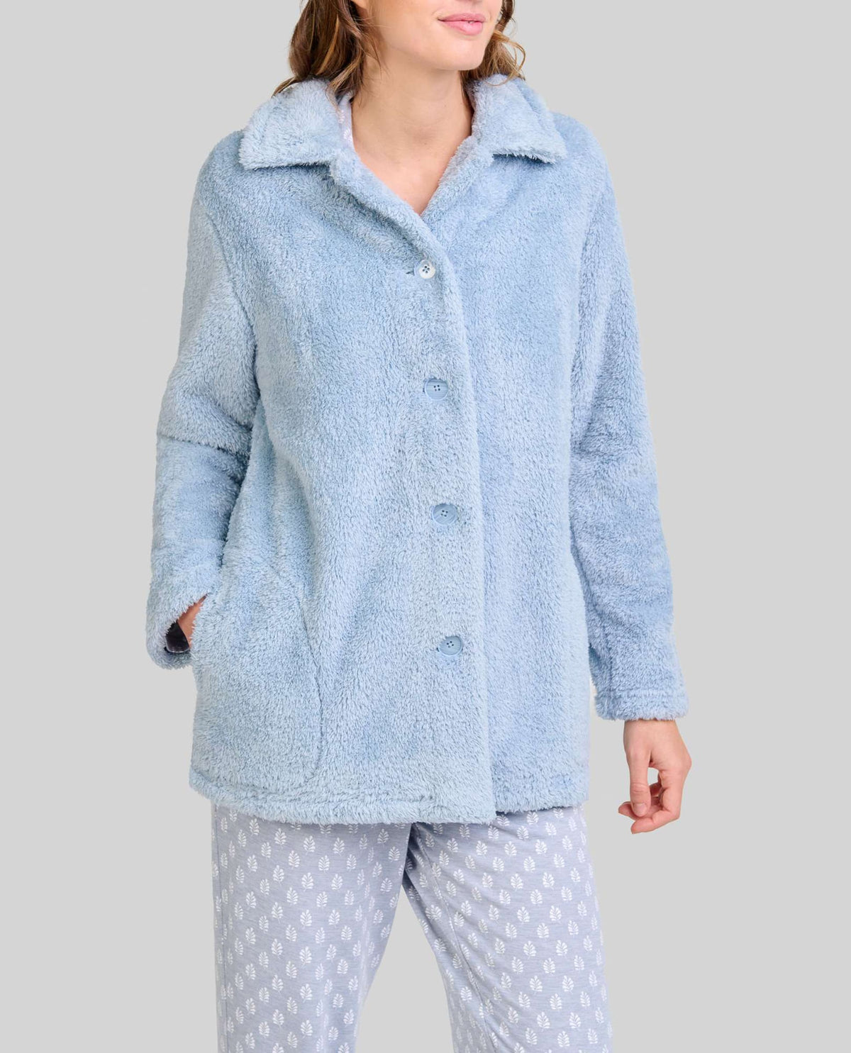 Mujer luce cómoda y actual bata corta de rizo azul acero abotonada con bolsillos