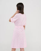 Vista trasera de mujer con bata rosa y estampado florecitas blancas