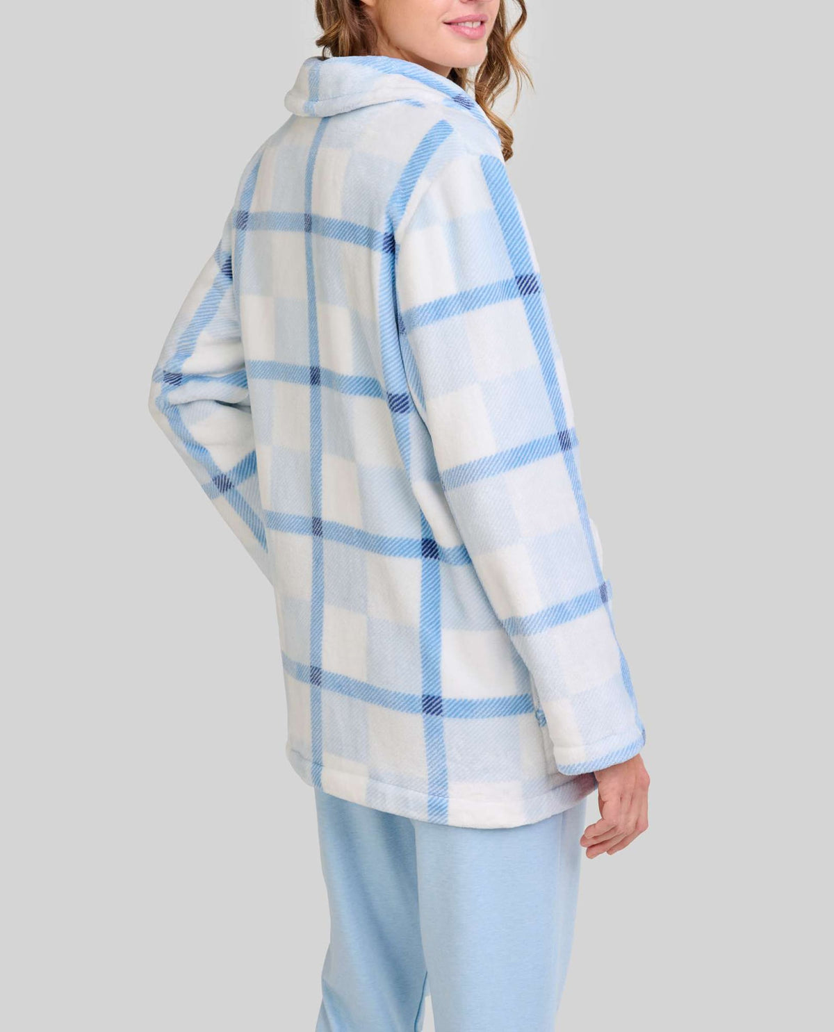 Mujer de espaldas luce bata corta polar azul claro con cuadros y pantalón azul con bolsillos