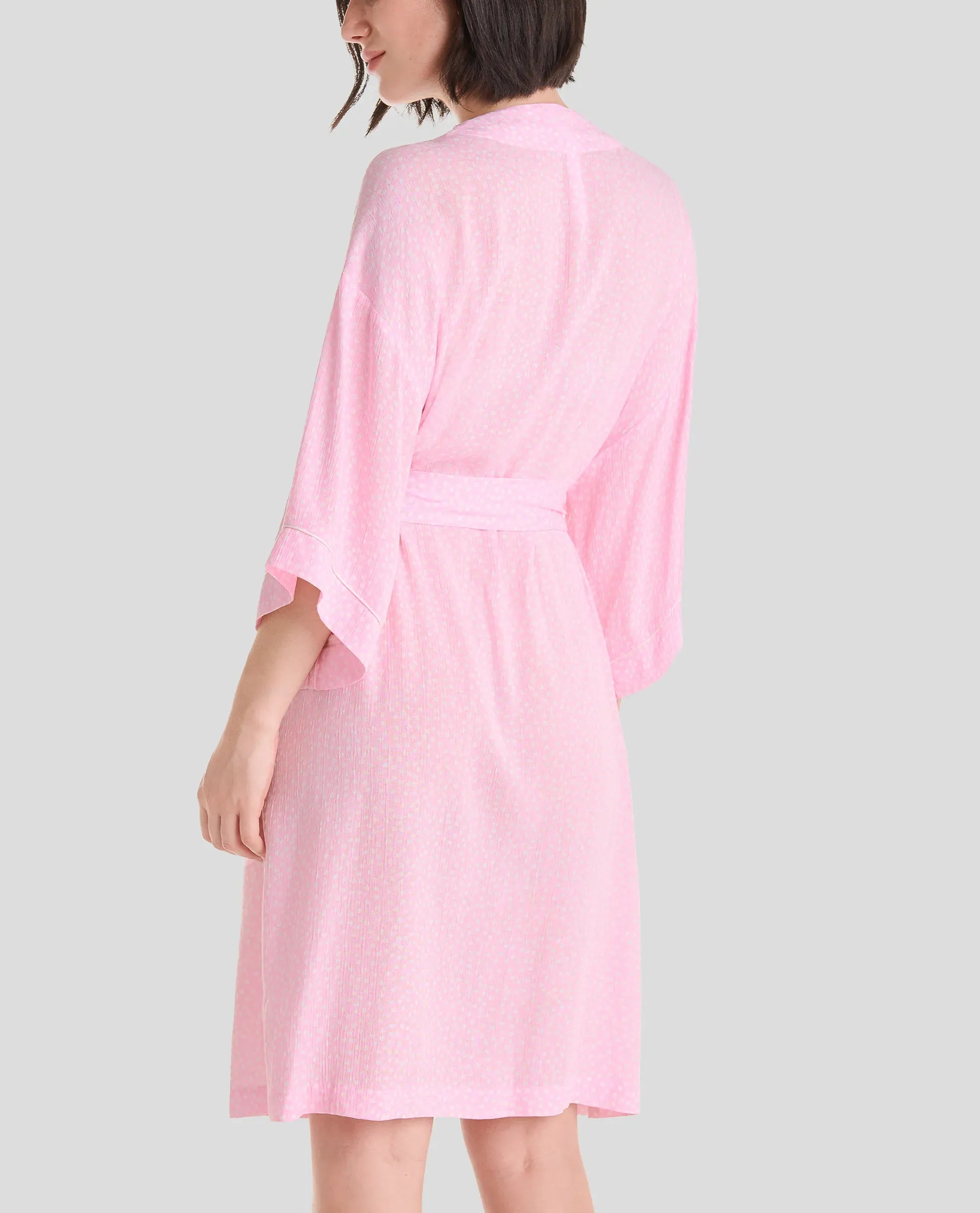 Mujer de espaldas luce elegante bata de verano con manga francesa en color rosa a topitos, con cinturón y bolsillos laterales - Rosa